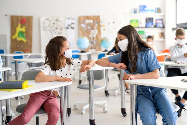 Children with face mask back at school after covid-19 quarantine and lockdown, greeting