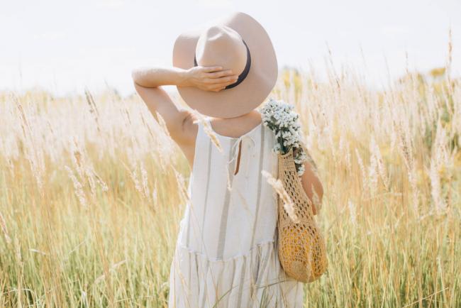 Woman wearing eco-friendly fashionable dress made of organic cotton standing in a field