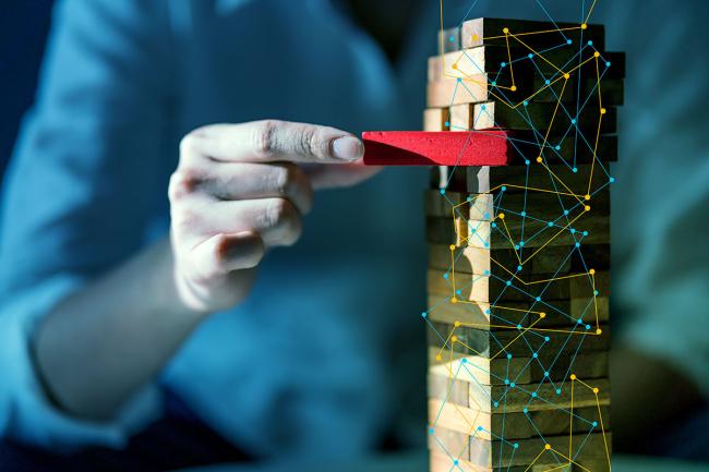 Why L&D Is Key in New Revenue and Mitigating Risk Businessperson working a Jenga tower business risk metaphor