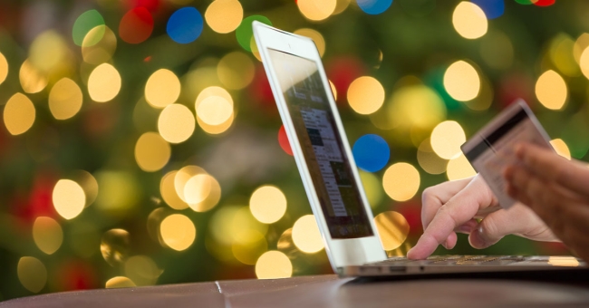 2021 Holidays to Stress-Test Retail – and how PLM Can Help Person doing holiday shopping using credit card on laptop