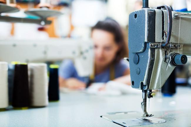 A seamstress works with sewing machines Close-up of sewing machine with seamstress in background