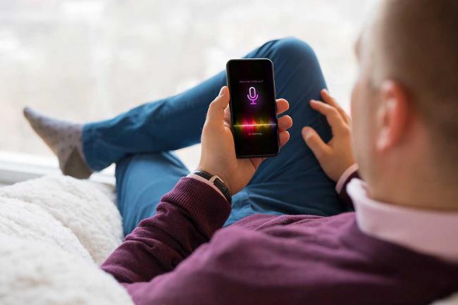 A man uses the virtual assistant on his smartphone Man using virtual assistant on smartphone