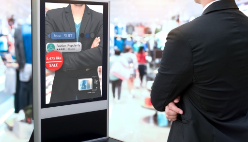 Man standing in front of an augmented reality mirror at a store showing the prices of the items he is trying on
