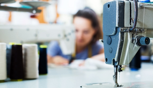 Close-up of sewing machine with seamstress in background