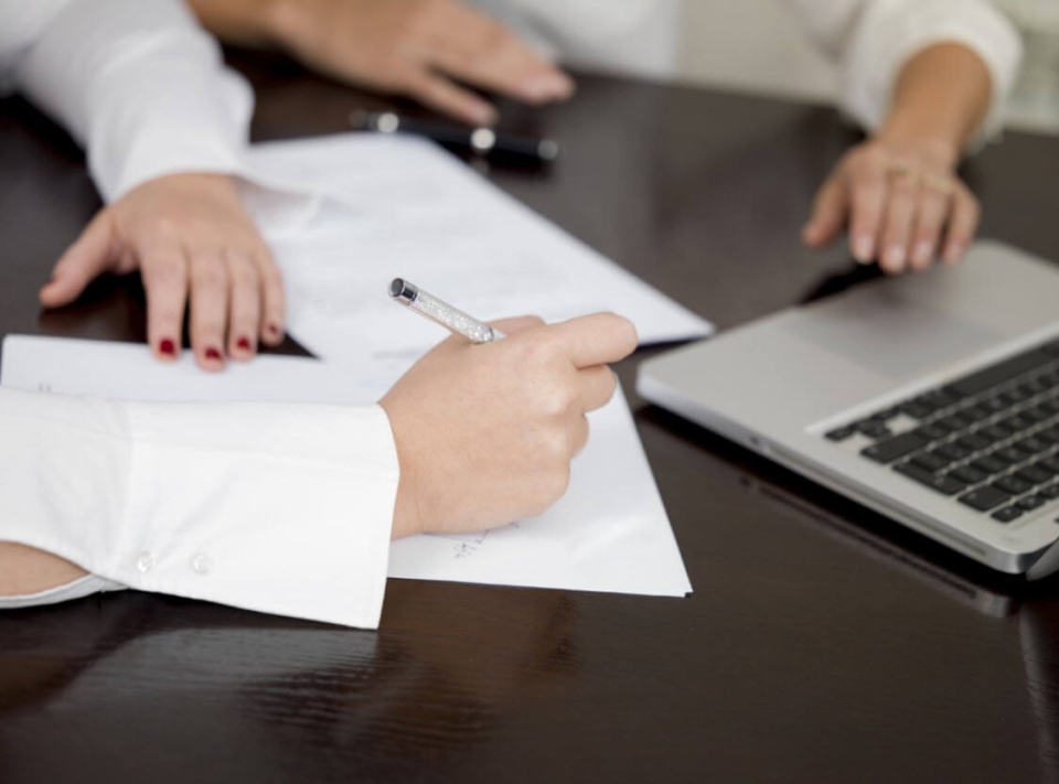 A team sitting at a conference room table building a business case on a laptop